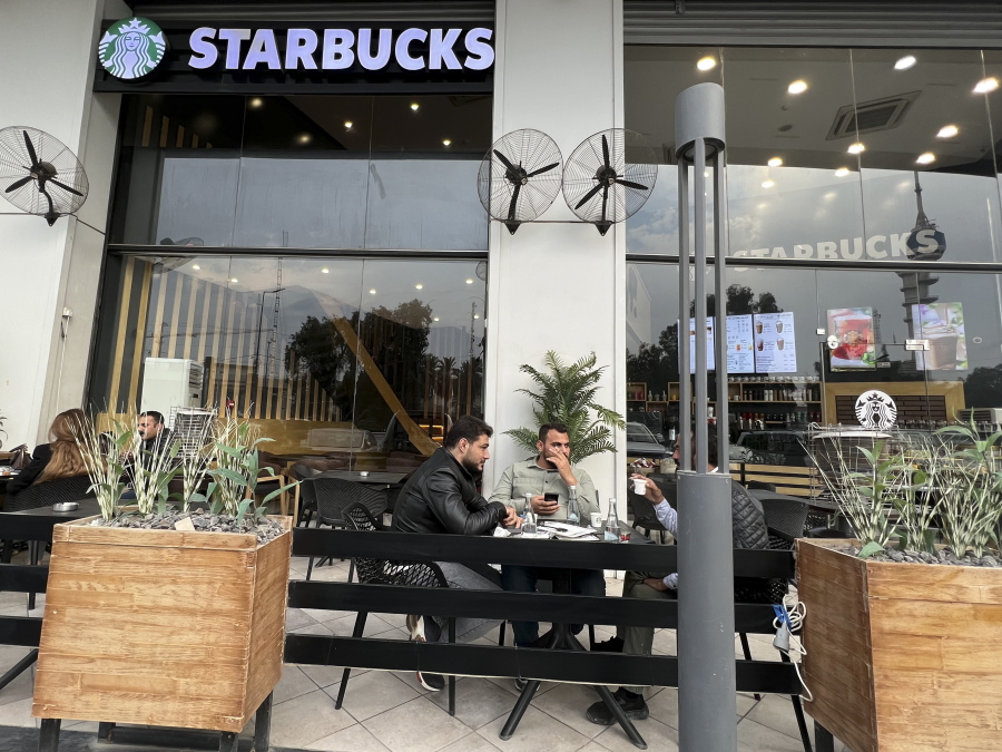 People sit in an unlicensed Starbucks cafe in Baghdad, Iraq, Wednesday, Dec. 21, 2022. Real Starbucks merchandise is imported from neighboring countries to stock the three cafes in the city, but all are unlicensed. Starbucks filed a lawsuit in an attempt to shut down the trademark violation but the case was shuttered after the owner allegedly threatened lawyers hired by the coffee house.