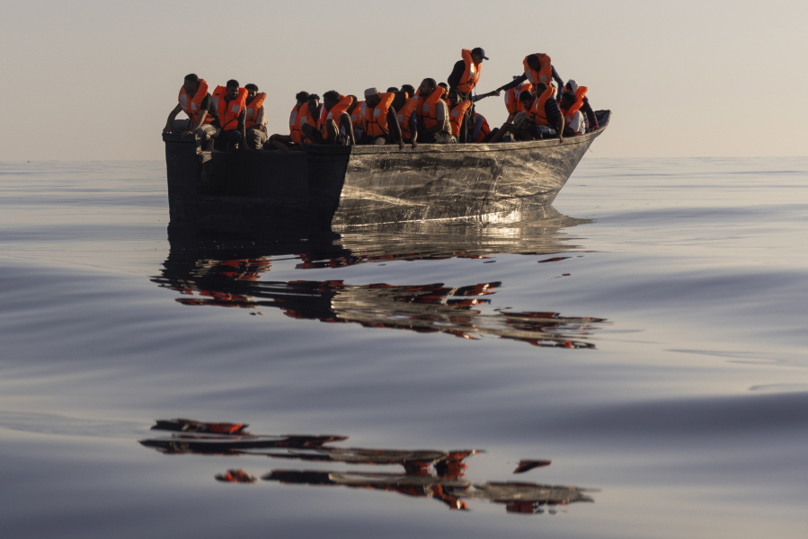 FILE - Migrants with life jackets provided by volunteers of the Ocean Viking, a migrant search and rescue ship run by NGOs SOS Mediterranee and the International Federation of Red Cross (IFCR), still sail in a wooden boat as they are being rescued some 26 nautical miles south of the Italian Lampedusa island in the Mediterranean sea, Saturday, Aug. 27, 2022. Charities that rescue migrants at sea complained Thursday, Dec. 29, 2022, that new measures adopted by Italy government will limit their rescue capacity, risking lives at sea.