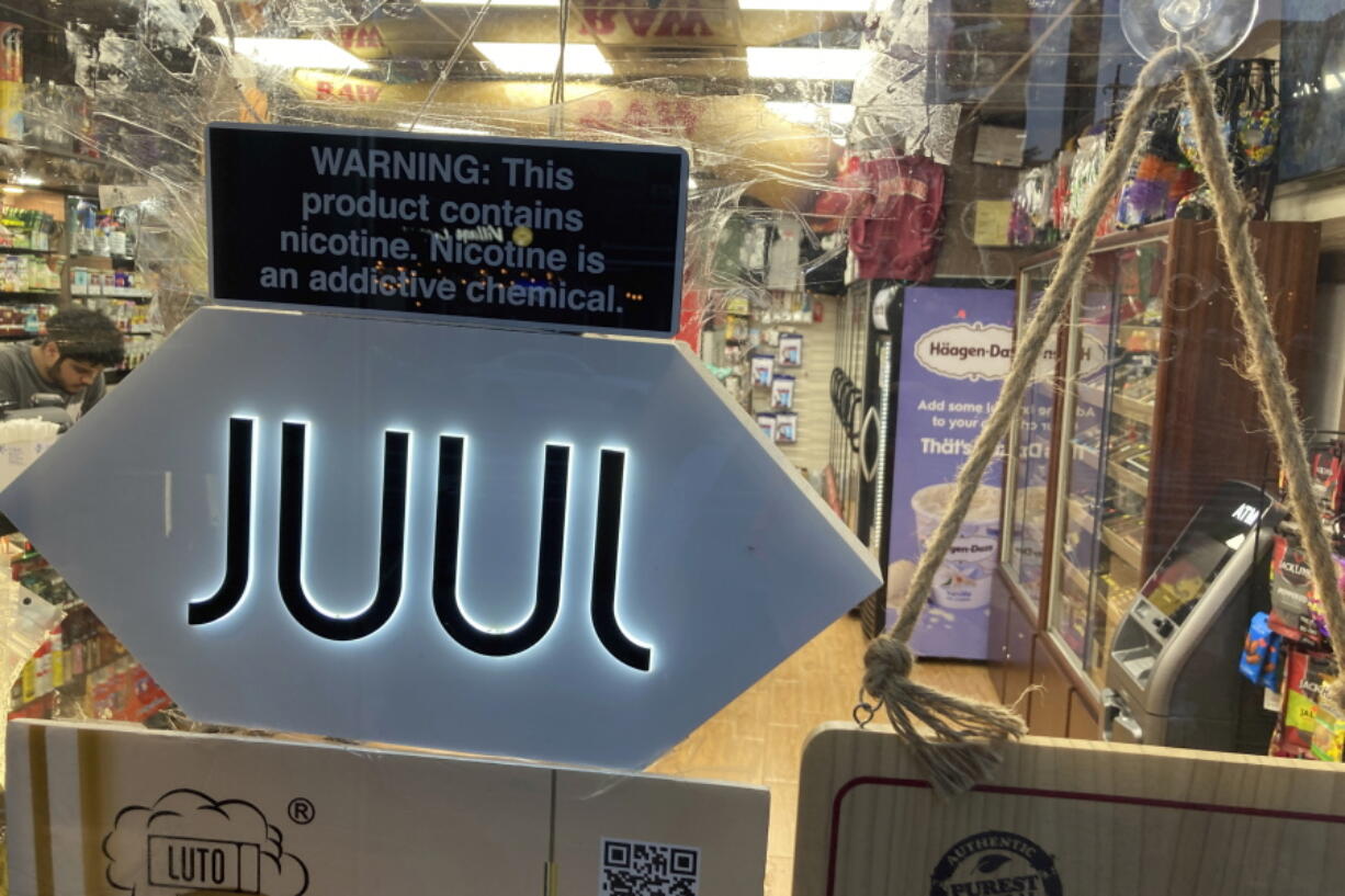 FILE - A Juul sign hangs in the front window of a bodega convenience store in New York City on June 25, 2022. Electronic cigarette maker Juul Labs has reached settlements covering more than 5,000 cases brought by about 10,000 plaintiffs related to its vaping products. Financial terms of the settlement were not disclosed, but Juul said that it has secured an equity investment to fund it. The company has been buffeted by lawsuits and chances that it would seek bankruptcy protection, or a buyer, were elevated last month as Juul announced hundreds of layoffs and secured new financing to  continue operations.