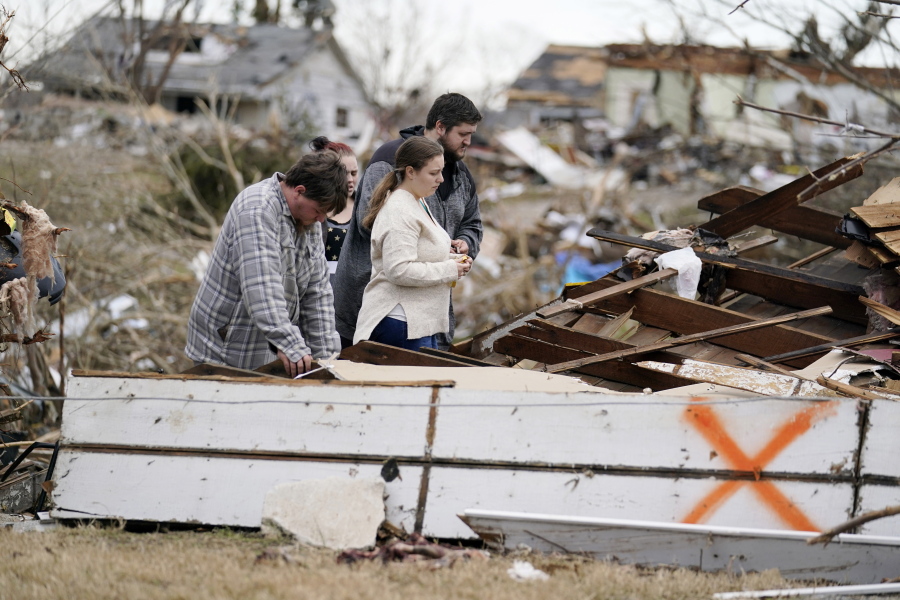 FILE -Brandon Clark, behind, injured from the tornado, returns to his destroyed home for the first time with Laura Shepherd, Tyler Shepherd, left, and his wife Georgialee Clark, behind in the aftermath of tornadoes that tore through the region, in Dawson Springs, Ky., Wednesday, Dec. 15, 2021. One year ago Saturday, Dec. 10, 2022, a massive tornado obliterated wide swaths of  Dawson Springs, Ky.