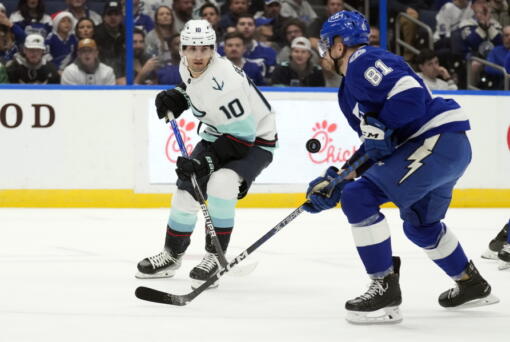 Seattle Kraken center Matty Beniers (10) and Tampa Bay Lightning defenseman Erik Cernak (81) chase a bouncing puck during the first period of an NHL hockey game Tuesday, Dec. 13, 2022, in Tampa, Fla.