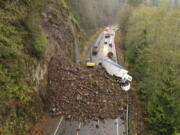 In this photo provided by the Oregon Department of Transportation, crews work to clear debris and remove a disabled truck on U.S. 30 east of Astoria, Ore., Wednesday, Nov. 30, 2022, after a landslide Tuesday night.