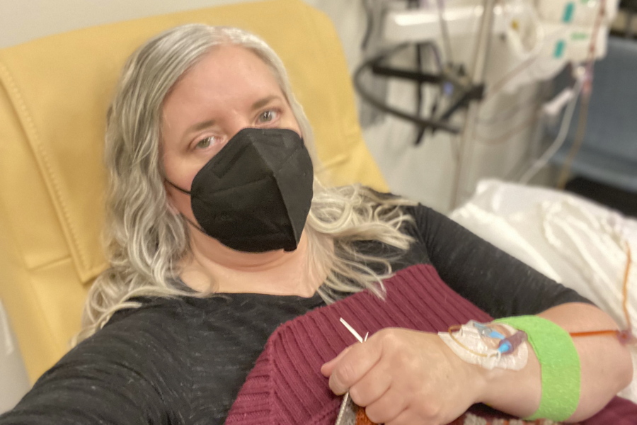 This photo provided by Amy Watson of Portland, Ore., shows her during an iron infusion in December 2022. Watson, approaching 50, says she has "never had any kind of recovery" from COVID-19. She has had severe migraines, plus digestive, nerve and foot problems. Recently she developed severe anemia.