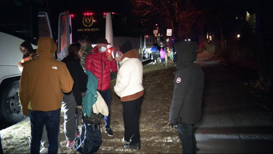 This image provided by WJLA shows migrant families as they get on to a bus to transport them from near the Vice President's residence to an area church after they arrived in Washington, Saturday, Dec. 24, 2022. Local organizers in Washington say three buses of recent migrant families arrived from Texas near the home in record-setting cold on Christmas Eve. Texas authorities have not confirmed their involvement.