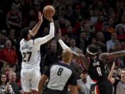 Denver Nuggets guard Jamal Murray, left, hits a 3-pointer with less than a second left in the NBA basketball game as Portland Trail Blazers forward Jerami Grant, right, defends in Portland, Ore., Thursday, Dec. 8, 2022. The Nuggets won 121-120.