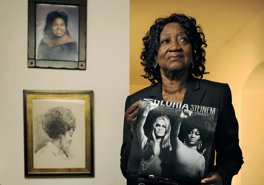 Dorothy Pitman Hughes poses in her St. Johns, Fla., home on Sept.  24, 2013, with a poster using a 1970's image of herself and Gloria Steinem. Hughes, a pioneering Black feminist, child welfare advocate and activist who co-founded Ms. Magazine with Steinem, formed a powerful speaking partnership with her and appeared with her in one of the most iconic photos of the feminist movement, has died. Hughes died Dec. 1, 2022, in Tampa, Fla.  She was 84.