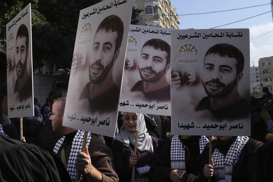 Palestinians hold posters of Palestinian prisoner Nasser Abu Hamid during a protest in front of the International Committee of the Red Cross office, Tuesday, Dec. 20, 2022, in Gaza City, after he died of lung cancer in Israel. Abu Hamid was a former leader of the Al Aqsa Martyrs' Brigade, the armed wing of Palestinian President Mahmoud Abbas's Fatah party. He had been serving seven life sentences after being convicted in 2002 for involvement in the deaths of seven Israelis during the second Palestinian intifada, or uprising, against Israel's occupation in the early 2000s. Arabic reads: " Nasser Abu Hamid is a martyr".