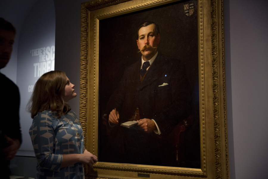 FILE - A Museum of London employee poses for photographers next to an 1897 oil on canvas portrait of Sherlock Holmes author Sir Arthur Conan Doyle by illustrator Sidney Paget on display as part of the exhibition "Sherlock Holmes: The Man Who Never Lived and Will Never Die" at the Museum of London in London, Oct. 16, 2014. Sherlock Holmes is finally free to the public in 2023. The long dispute on contested copyright on Doyle's tales of a whip-smart detective will come to an end in 2022, as the final Sherlock Holmes stories by Doyle will be released on Saturday, Dec. 31, as copyrights from 1927 expire on Jan. 1, 2023.