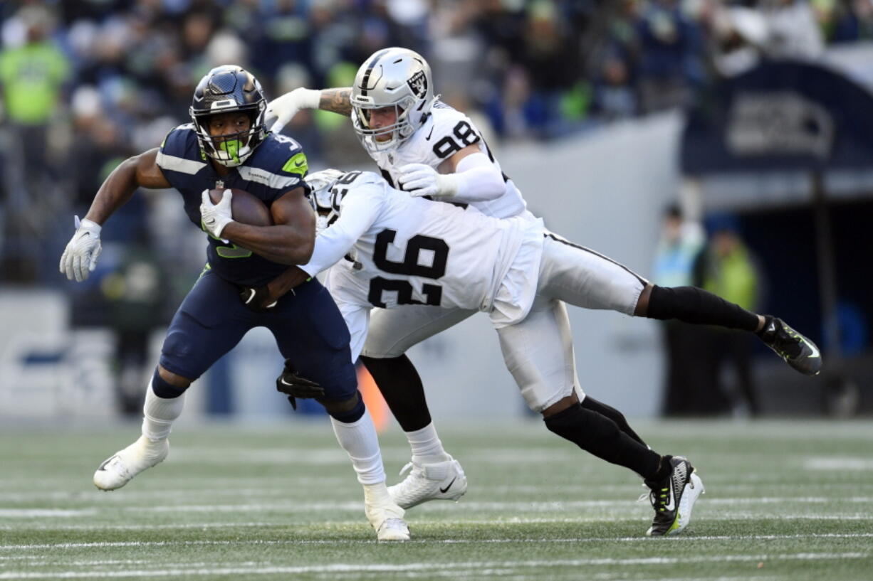 Seattle Seahawks running back Kenneth Walker III (9) runs past Las Vegas Raiders cornerback Rock Ya-Sin (26) and defensive end Maxx Crosby (98) during the first half of an NFL football game Sunday, Nov. 27, 2022, in Seattle.