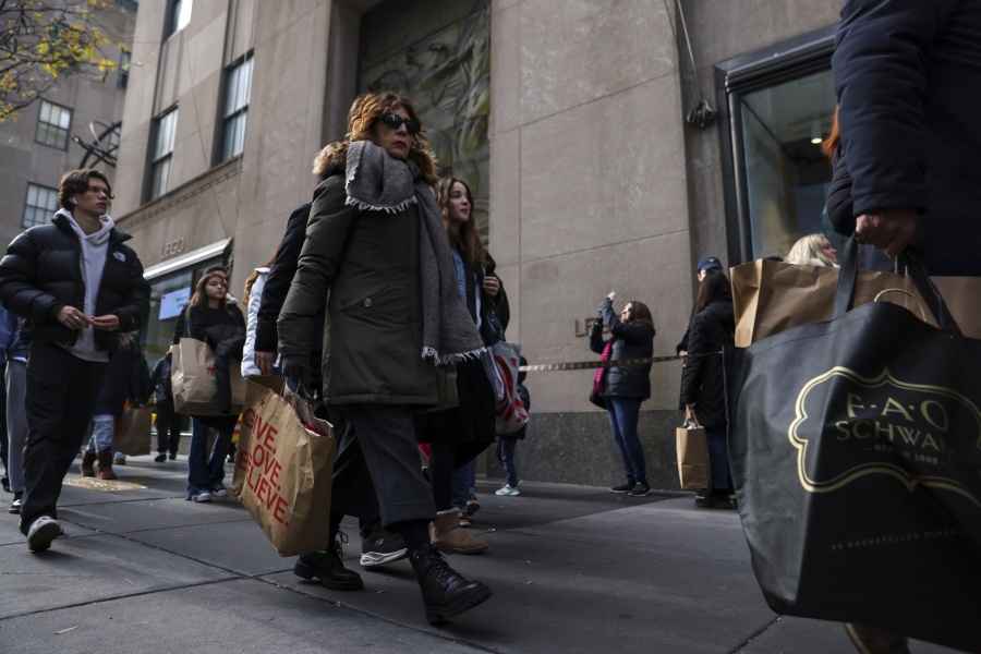 Shoppers carry bags down Fifth Avenue on  Friday, Nov. 25, 2022, in New York. The Commerce Department releases retail sales data for November on Friday, Dec.