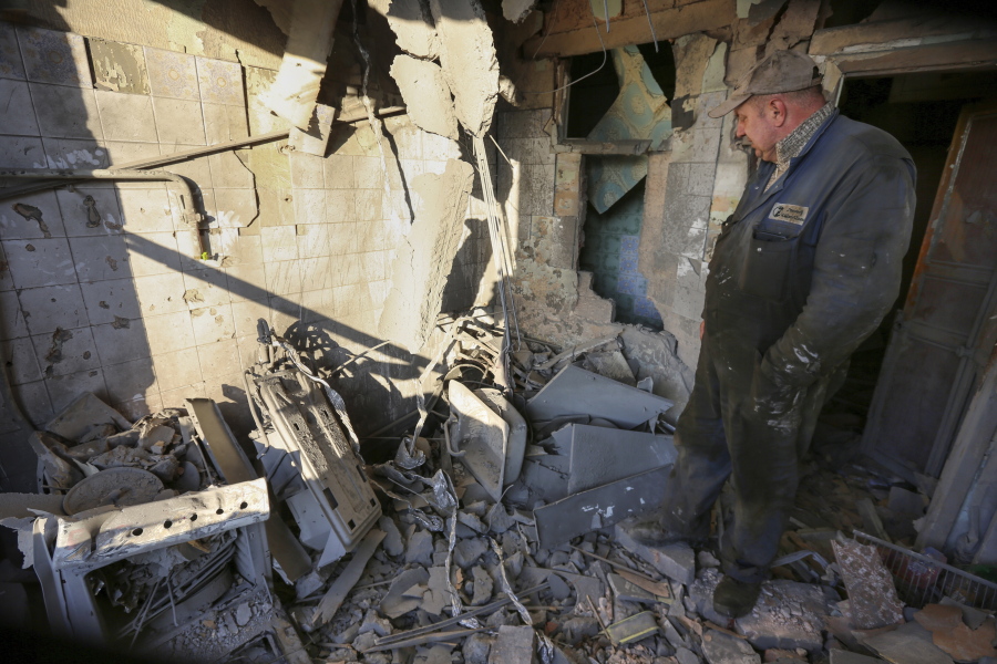 A man examines a damaged apartment building after what Russian officials in Donetsk said was a shelling by Ukrainian forces, in Donetsk, the capital of Russian-controlled Donetsk region, eastern Ukraine, Thursday, Dec. 15, 2022.