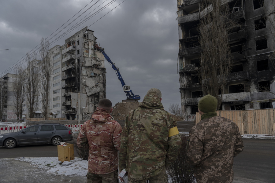 Servicemen watch as a bombed building is dismantled in Borodyanka, Kyiv region, Ukraine, Tuesday, Dec. 13, 2022.