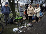 FILE - Local residents gather near a generator to charge their mobile devices in an area controlled by Russian-backed separatist forces in Mariupol, Ukraine, Friday, April 22, 2022. When Russian forces two months ago launched a military campaign against infrastructure in Ukraine, it opened an urgent second front far from the contact line: Along power lines, water mains, and heating systems, and in places like homes, schools, offices and churches.