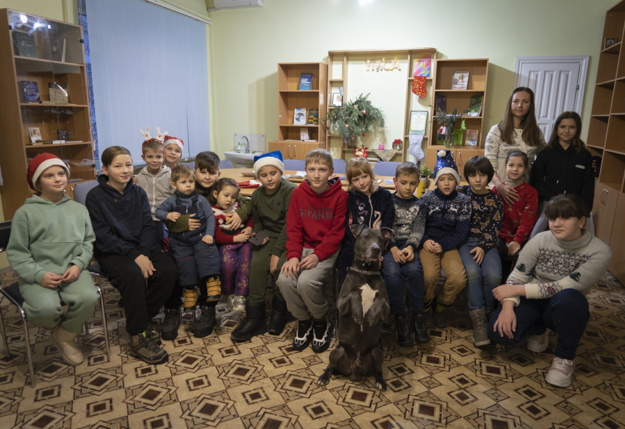 Children traumatized by the war pose for photo with an American Pit Bull Terrier "Bice" in the Center for Social and Psychological Rehabilitation in Boyarka close Kyiv, Ukraine, Wednesday, Dec. 7, 2022. Bice is an American pit bull terrier with an important and sensitive job in Ukraine -- comforting children traumatized by the war. The Center for Social and Psychological Rehabilitation is a state-operated community center where a group of people are trying to help those who have experienced a trauma after the Feb. 24 Russian invasion, and now they are using dogs like Bice to give comfort.