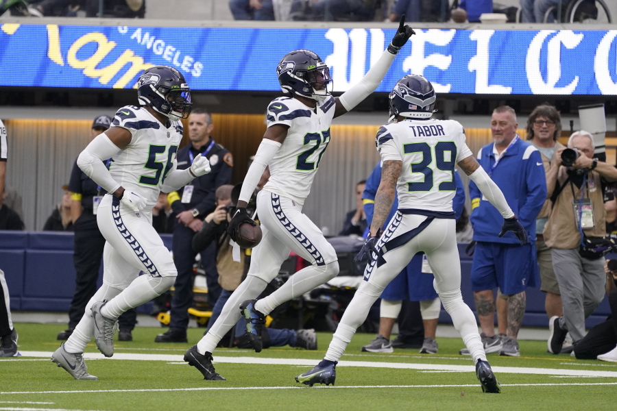 Seattle Seahawks cornerback Tariq Woolen, center, celebrates after intercepting a pass as teammates Jordyn Brooks (56) and Teez Tabor (39) watch during the first half of an NFL football game against the Los Angeles Rams Sunday, Dec. 4, 2022, in Inglewood, Calif. (AP Photo/Mark J.