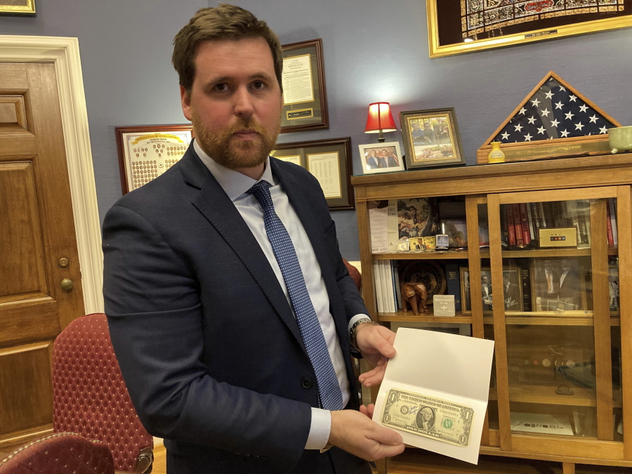 Missouri Treasurer Scott Fitzpatrick displays a $1 bill signed by the former treasurer of the United States on Thursday, Dec. 15, 2022, at his Capitol office in Jefferson City, Mo. Due partly to rising interest rates, Missouri had earned more than $116 million on investments through the first five months of its current fiscal year -- nearly double the amount earned the entire previous year. (AP Photo/David A.