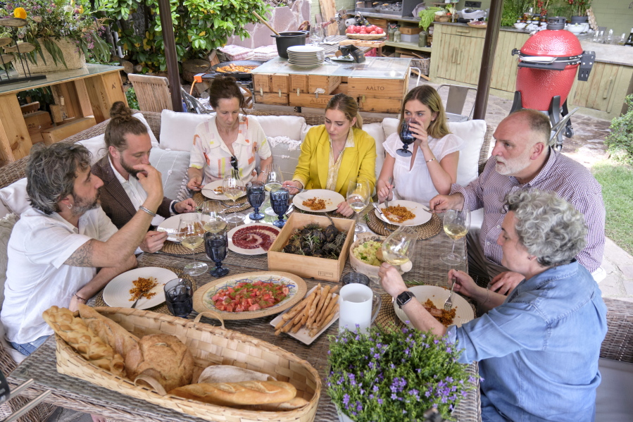 Diego Guerrero, from left, Carlos Sanchez, Mila, Ines Andres, Carlota Andres, Jose Andres and Pepa Mu?oz enjoy a meal the chefs prepared at Mu?oz's house in a scene from the Discovery + television series "Jose Andres and Family in Spain." (Xaume Olleros/Discovery)