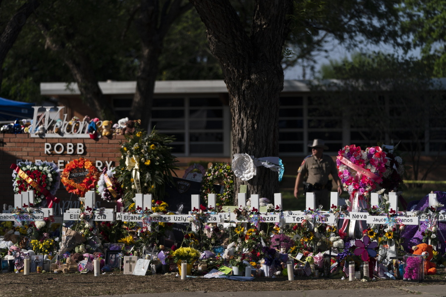 FILE - Flowers and candles are placed around crosses on May 28, 2022, at a memorial outside Robb Elementary School in Uvalde, Texas, to honor the victims killed in the school shooting a few days prior. Victims of the Uvalde school shooting that left 21 people dead have filed a lawsuit seeking $27 billion against local and state police, the city and other school and law enforcement officials for failing to follow active shooter protocol because authorities waited more than an hour to confront the attacker inside a fourth-grade classroom, according to court documents. (AP Photo/Jae C.