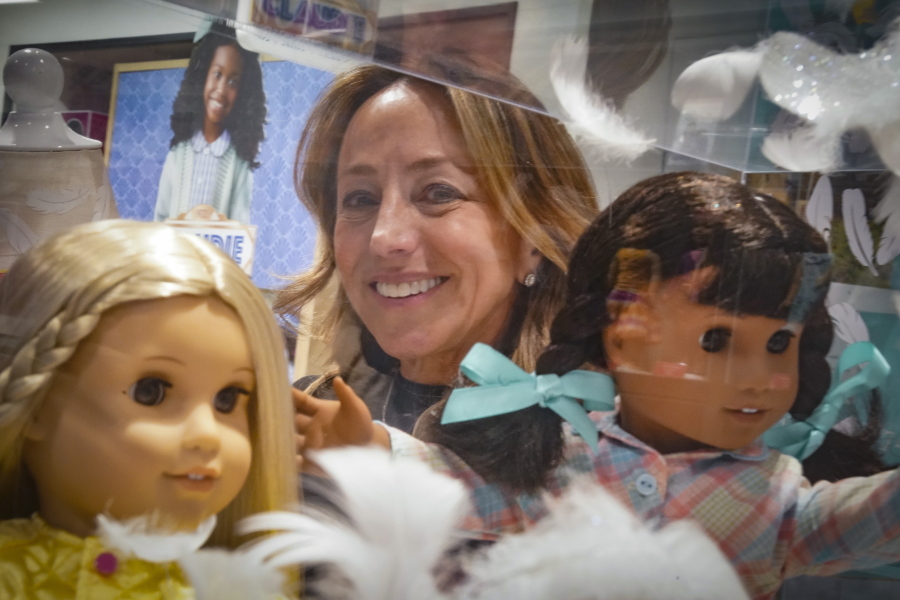 Jamie Cygielman, general manager and president at American Girl, poses behind a showcase of dolls during a press tour, Friday, Dec. 2, 2022, in New York. Cygielman said she first discovered interest from adults for toys of their own after the launch of the 17th historical doll Courtney Moore in late 2020.
