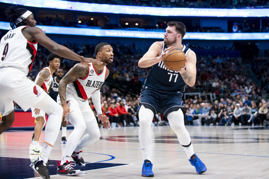 Dallas Mavericks guard Luka Doncic (77) looks to pass the ball as Portland Trail Blazers guard Damian Lillard (0) defends against him in the first half of an NBA basketball game in Dallas, Friday, Dec. 16, 2022.