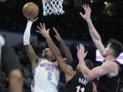 Oklahoma City Thunder guard Shai Gilgeous-Alexander (2) shoots in front of Portland Trail Blazers guard Josh Hart (11) and =ppo24=, right, in the second half of an NBA basketball game Monday, Dec. 19, 2022, in Oklahoma City.