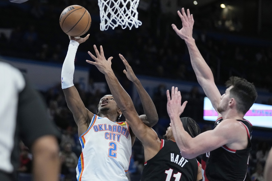 Oklahoma City Thunder guard Shai Gilgeous-Alexander (2) shoots in front of Portland Trail Blazers guard Josh Hart (11) and =ppo24=, right, in the second half of an NBA basketball game Monday, Dec. 19, 2022, in Oklahoma City.