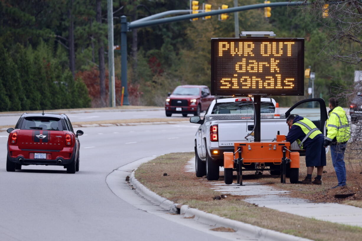 Workers set up an automated display warning drivers on NC211 of the power outage in the area and how to approach the upcoming intersections in Southern Pines, N.C., Monday, Dec. 5, 2022.