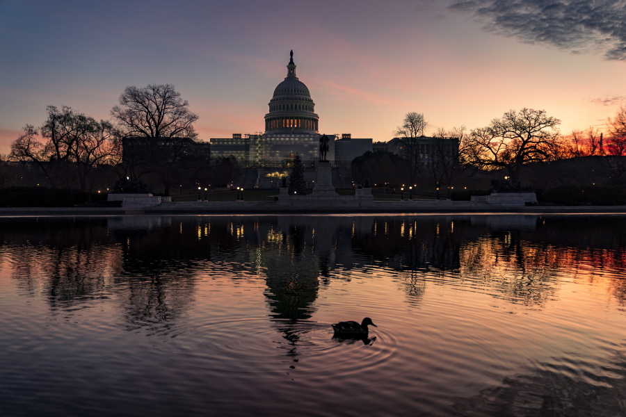 FILE - The sun rises behind the Capitol in Washington, early Wednesday, Dec. 14, 2022. Congressional leaders have unveiled a $1.7 trillion spending package early Tuesday, Dec. 20, 2022, that includes another large round of aid to Ukraine, a nearly 10% boost in defense spending and roughly $40 billon to assist communities across the country recovering from drought, hurricanes and other natural disasters. (AP Photo/J.