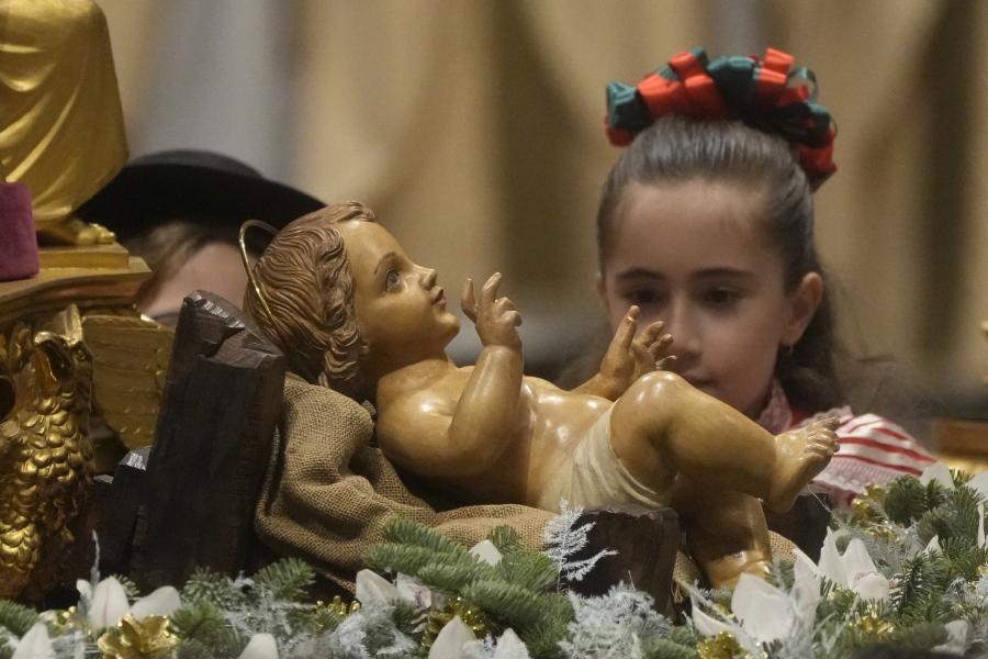 A girl looks at a statue of Baby Jesus as Pope Francis presides over Christmas Eve Mass, at St. Peter's Basilica at the Vatican, Saturday Dec. 24, 2022.