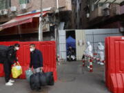 Migrant workers with their belongings leave a barricaded village after authorities' easing of COVID-19 curbs in Haizhu district in Guangzhou in south China's Guangdong province on Friday, Dec. 2, 2022. Local Chinese authorities on Saturday announced a further easing of COVID-19 curbs, with major cities such as Shenzhen and Beijing no longer requiring negative tests to take public transport.
