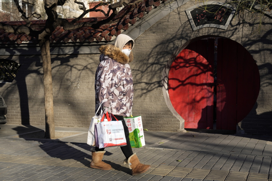 A resident wearing mask past by a traditional entrance way in Beijing, Friday, Dec. 16, 2022. A week after China dramatically eased some of the world's strictest COVID-19 containment measures, uncertainty remained Thursday over the direction of the pandemic in the world's most populous nation.