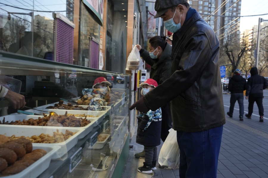 Residents go about their life with some shops re-opening for business as restrictions are eased in Beijing, Saturday, Dec. 3, 2022. Chinese authorities on Saturday announced a further easing of COVID-19 curbs with major cities such as Shenzhen and Beijing no longer requiring negative tests to take public transport.