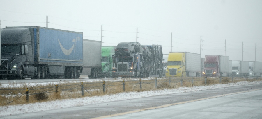 Tractor trailers are stacked up on the shoulder along the eastbound lanes of Interstate 70 near East Airpark Road, Tuesday, Dec. 13, 2022, in Aurora, Colo. A massive winter storm has closed roads throughout northeast Colorado.