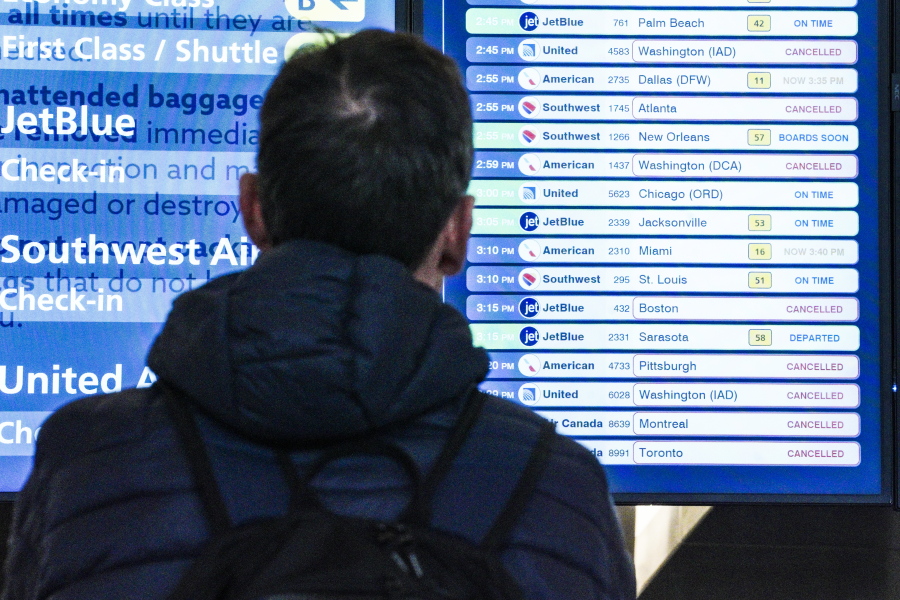 A passenger checks flight departures showing cancellations at Laguardia Airport, Friday Dec. 23, 2022, in New York.