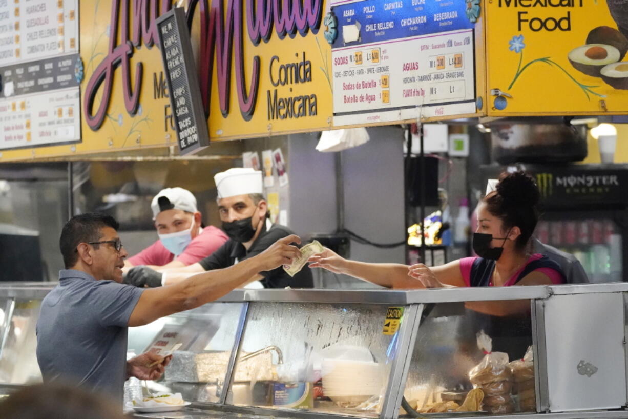 FILE - Money is exchanged at a food stand inside Grand Central Market on Wednesday, July 13, 2022, in Los Angeles. U.S. inflation, an economic afterthought for decades, returned in 2022 with the relentless rise in prices devouring workers' pay and putting American consumers in a foul mood.