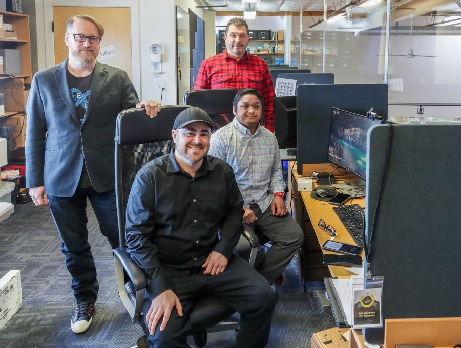 From left, Bill Landon, Kyle McCormick, Justin Fernandez, and Jim Dixon, standing, make up a small Ballard IT-services company on Dec. 21, 2022, in Seattle. Dixon says hiring is now easier, because there are more people looking for work.