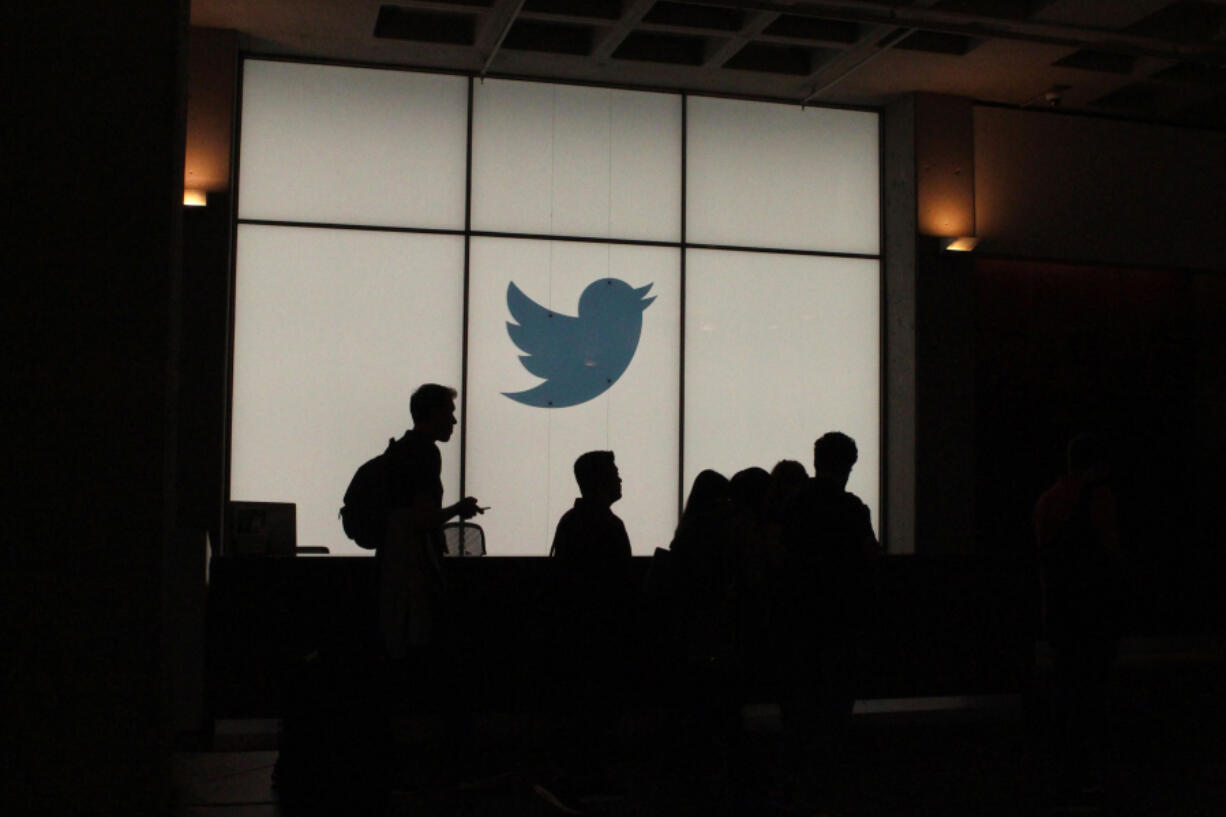 Employees walk past a lighted Twitter logo as they leave the company's headquarters in San Francisco on Aug. 13, 2019.