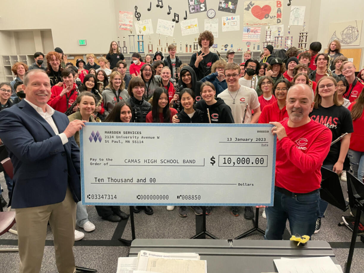 Camas High School band director Richard Mancini, right, accepts a $10,000 donation from CBM Systems' Benjamin Reng during band class on Friday.