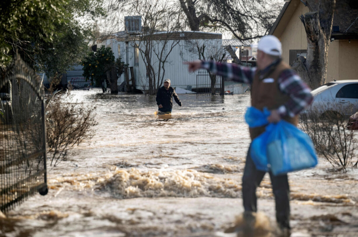 Residents scramble to retrieve belongings before flood waters rise too high in Merced, California, on Jan. 10, 2023.