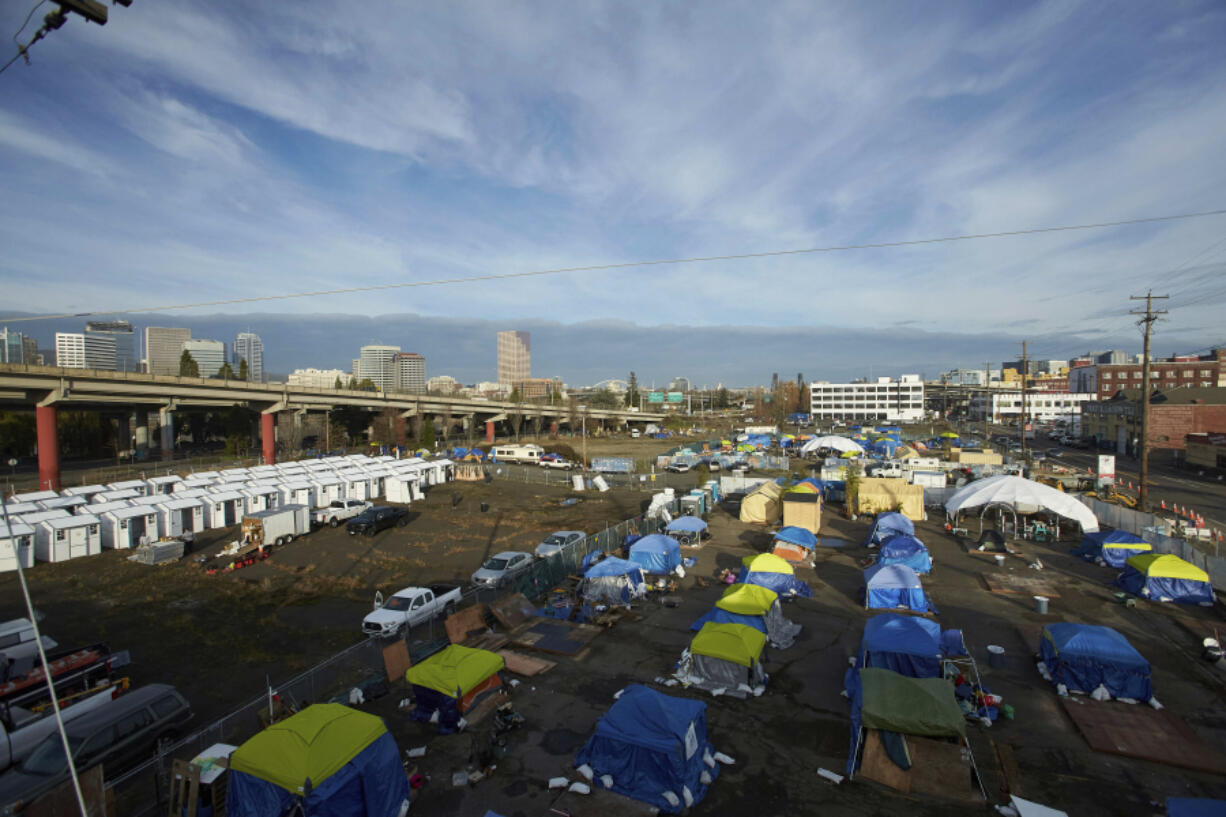 FILE - Homeless camps are seen in a vacant parking lot in Portland, Ore., Tuesday, Dec. 8, 2020. City Council members in Portland have voted to allocate $27 million of the city's budget to build a network of designated camping areas for homeless people.