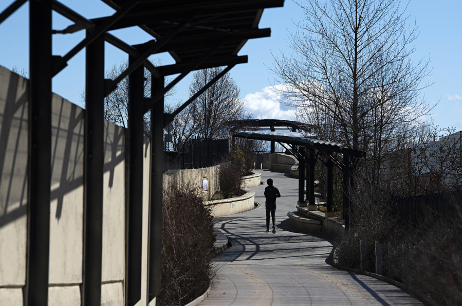 A jogger takes in some sunshine along a recently renovated and reopened Confluence Land Bridge in March 2022.