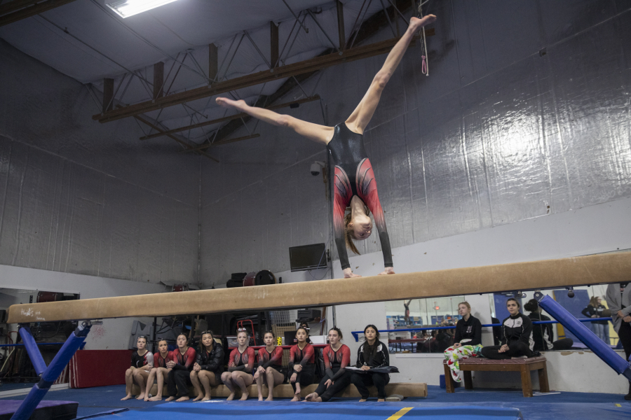 Lili Derkach of Union High School competes on the balance beam as her teammates look on during a gymnastics meet between Ridgefield, Camas, Union and Washougal at Naydenov Gymnastics on Dec. 17, 2022.