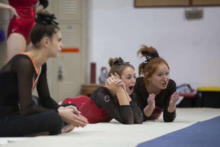 Camas gymnasts Kennedy Cody, right, and Cyenna McCusker cheer for a teammate during floor routines at Naydenov Gymnastics on Dec. 17.