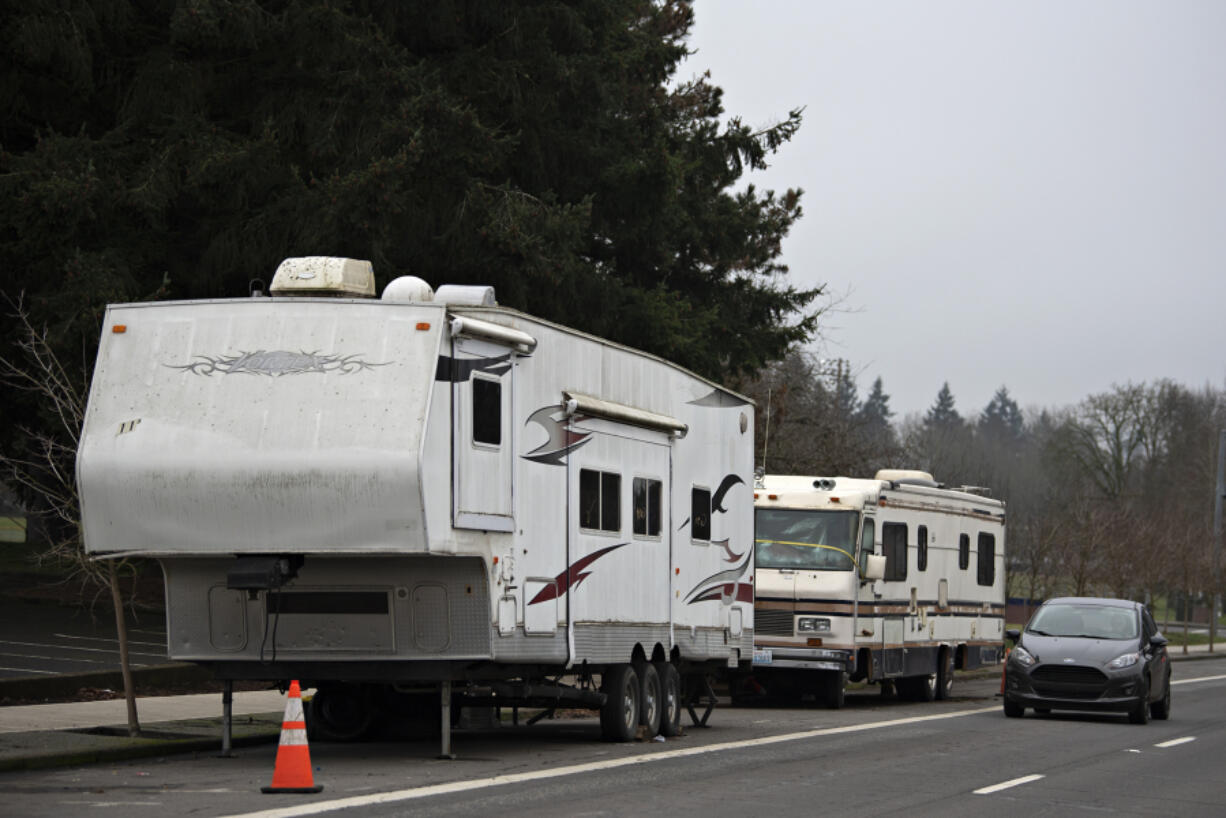A motorist traveling north on Fort Vancouver Way passes two recreational vehicles parked near Clark College, an area that has become home for several people living in their vehicles.