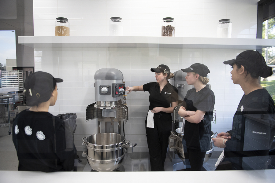 Allie Morgan of Crumbl Cookies, second from left, trains new employees Monday afternoon as the crew prepares for Friday's opening of the new store.
