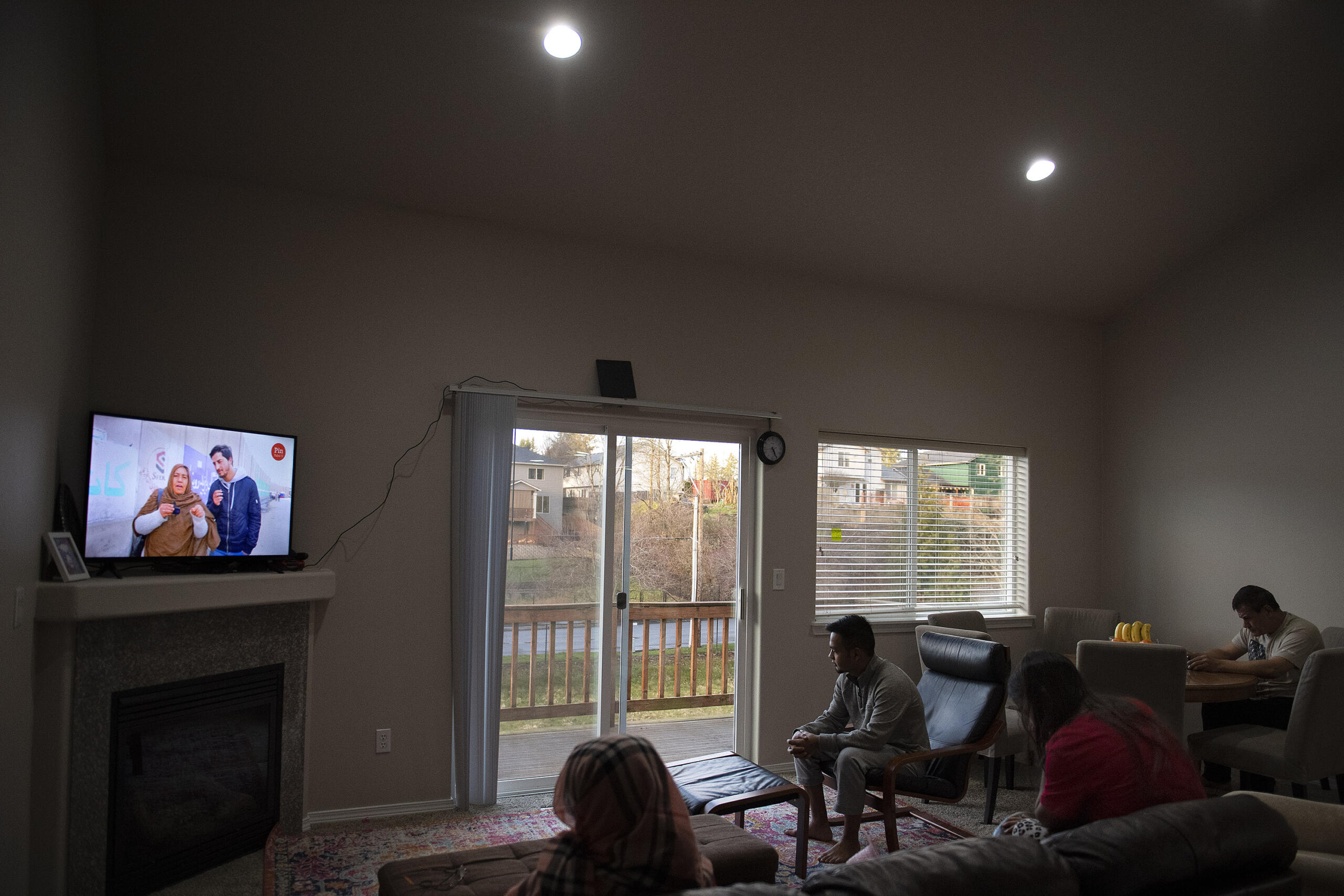 Sediqa Rustami, from left, Sajad Ibrahimi, Marwa Azizpour, and Mohammad Ismail Rezayee gather to watch a television channel from Afghanistan via YouTube on Sunday, Feb. 20, 2022 at their home.