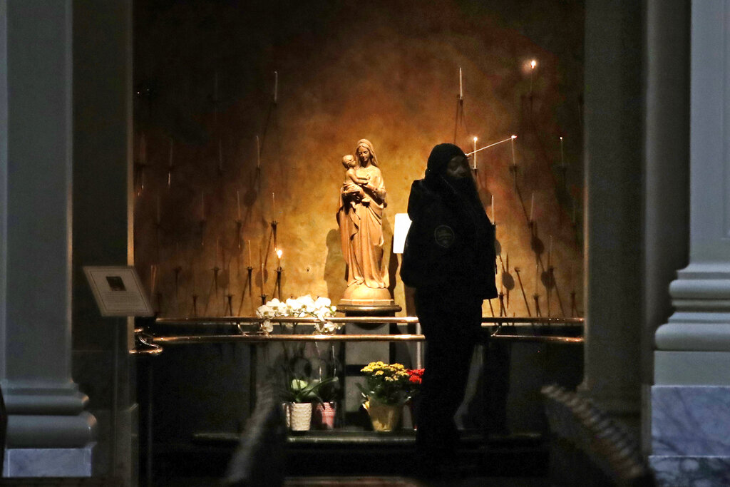 Kia Green lights a candle at St. James Cathedral, the Cathedral for the Catholic Archdiocese of Seattle, in an otherwise nearly empty sanctuary where hours have been limited because of the coronavirus outbreak Saturday, March 28, 2020, in Seattle.