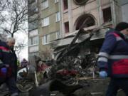 Workers pass the scene where a helicopter crashed on civil infrastructure in Brovary, on the outskirts of Kyiv, Ukraine, Wednesday, Jan. 18, 2023. The chief of Ukraine's National Police says a helicopter crash in a Kyiv suburb has killed 16 people, including Ukraine's interior minister and two children. He said nine of those killed were aboard the emergency services helicopter.