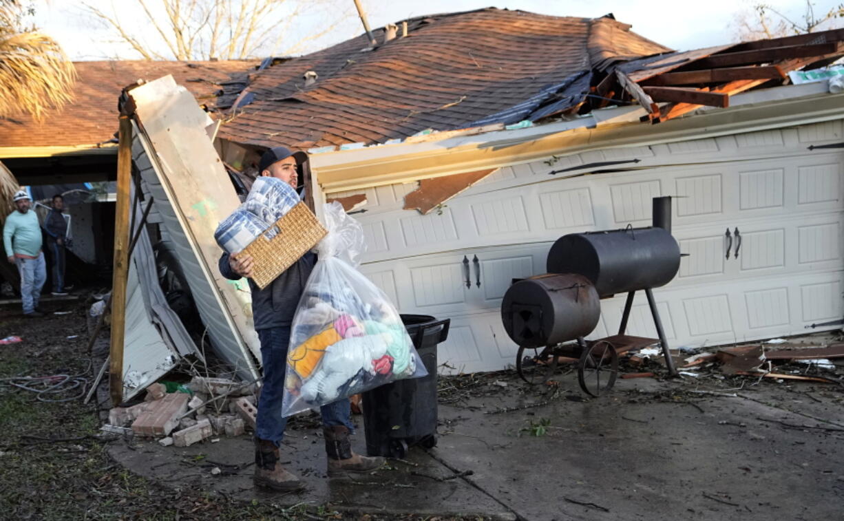 Mario Mendoza carries items out of a friend's storm-damaged home Tuesday, Jan. 24, 2023, in Pasadena, Texas. A powerful storm system took aim at Gulf Coast Tuesday, spawning tornados that caused damage east of Houston. (AP Photo/David J.