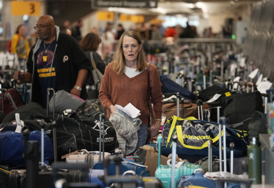 FILE - A traveler wades through a field of unclaimed bags at the Southwest Airlines luggage carousels at Denver International Airport, Dec. 27, 2022, in Denver. With its flights now running on a roughly normal schedule, Southwest Airlines is turning its attention to luring back customers and repairing damage to a reputation for service after canceling 15,000 flights around Christmas.